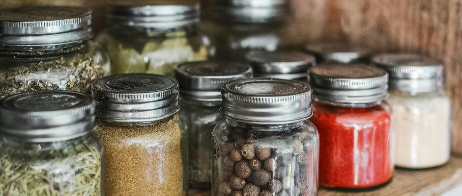Close-up of assorted spice jars with various herbs on a kitchen shelf, showcasing colorful culinary ingredients.